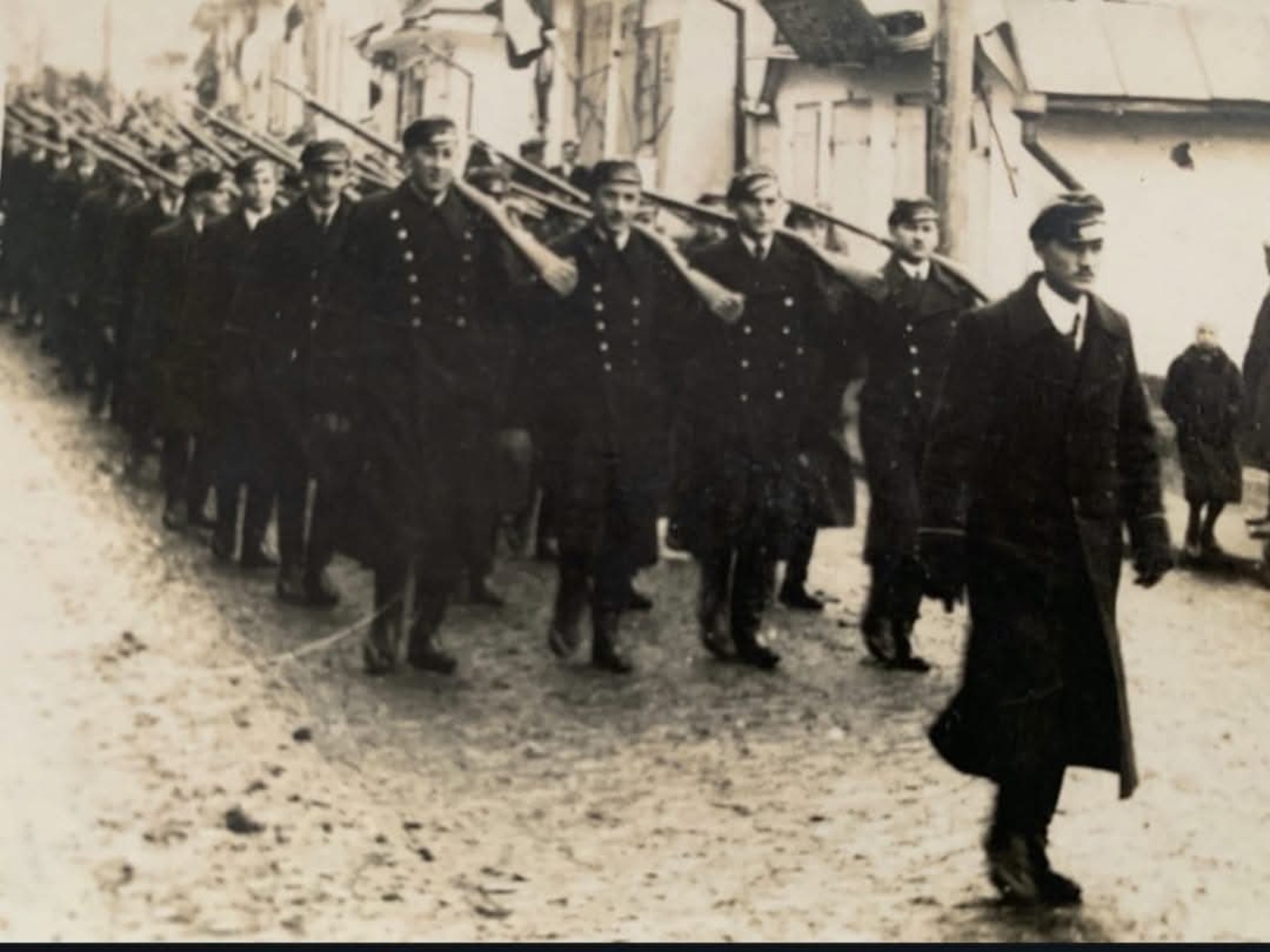 Defilada wojskowa pułku, w którym służył Adam Malach — kolumna maszerujących żołnierzy z karabinami na ramionach.