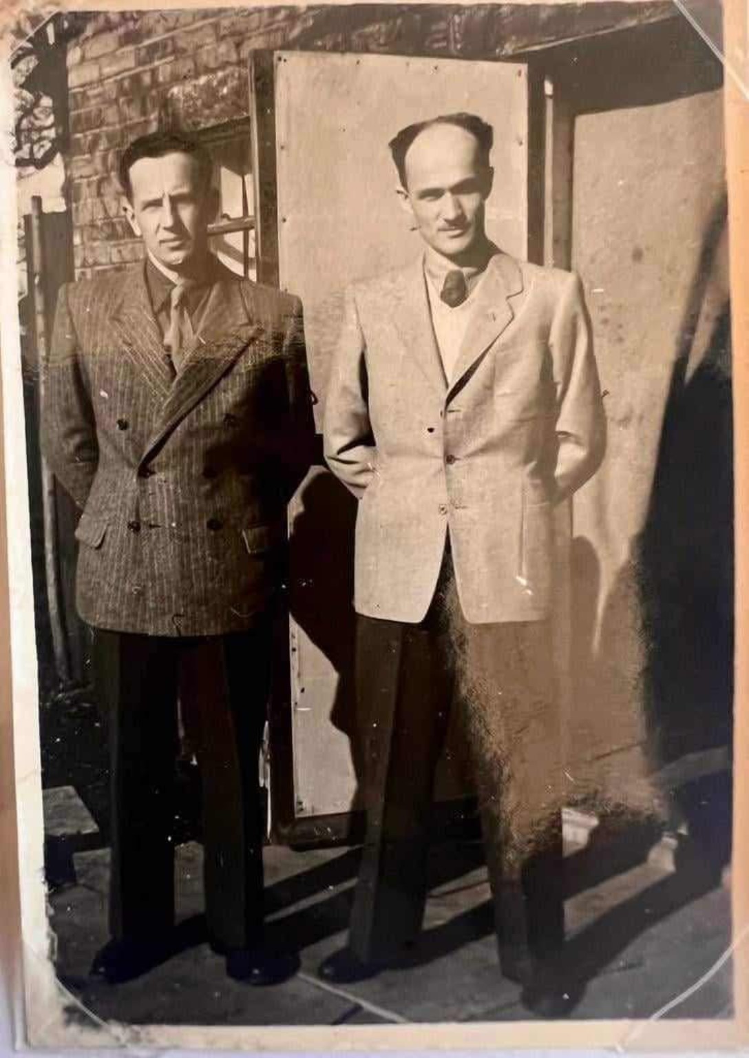 Jan i Adam Malachowie w garniturach przed wejściem do ceglanego budynku w Anglii — zgodnie z podpisem fotografii.